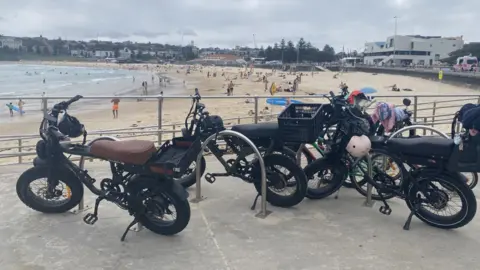 Helen Livingstone A row of fatbikes propped up on the promenade with a beach and ocean in the background