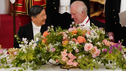 PA The Emperor and King laughing together, sat next to a large bouquet of flowers