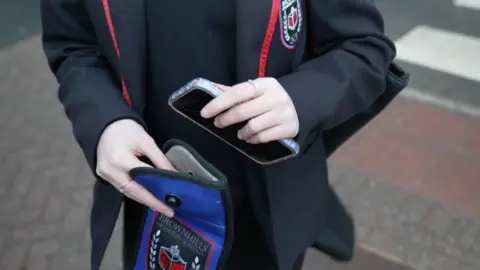 Hannah Karpel/BBC A school child with a phone pouch