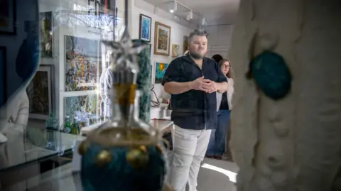 The artwork inspired by the seagrass and kelp projects on display in an exhibition space, with people milling around to look at the paintings, pottery and other work.