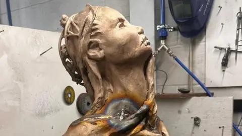 A close up of the head of the statue in a workshop