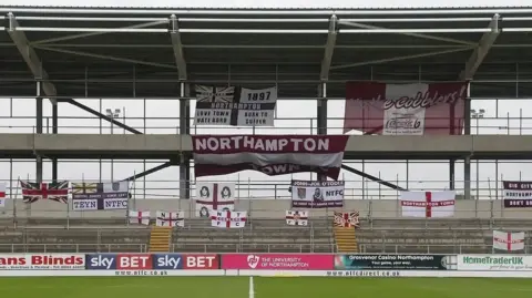 Getty Images A half-built shell of a football stand draped in supporter flags with the pitch in the foreground.