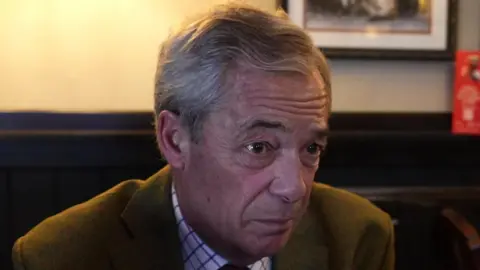 Nigel Farage with a burgundy tie, checked shirt and green blazer.