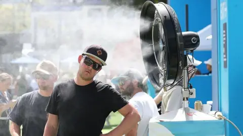 Man in black cools off with an electric fan