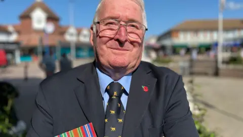 George Carden/BBC David Calvert taking part in the VJ Day commemoration in Hailsham town centre. He is wearing his father's war medals.