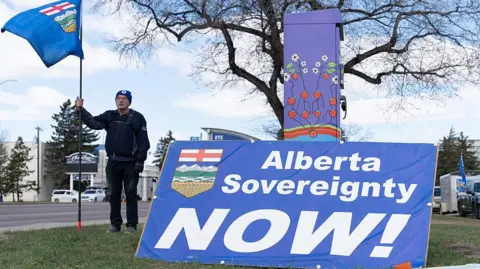 A separatist supporter holds a flag during a rally near the Elections Alberta headquarters in Edmonton, Canada, on May 4, 2026, as they submit boxes of signatures in the hope of triggering an independence referendum