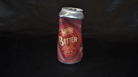 Trevor Prideaux A crushed can of bitter beer made by Moor brewery. The label is a mix of red and maroon.