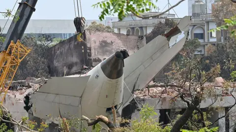 The wreckage of the crashed Air India plane is being lifted by a crane from the roof of the BJ Medical College mess building, on June 14, 2025 in Ahmedabad, India. 