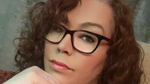 A woman with brown curly hair and glasses