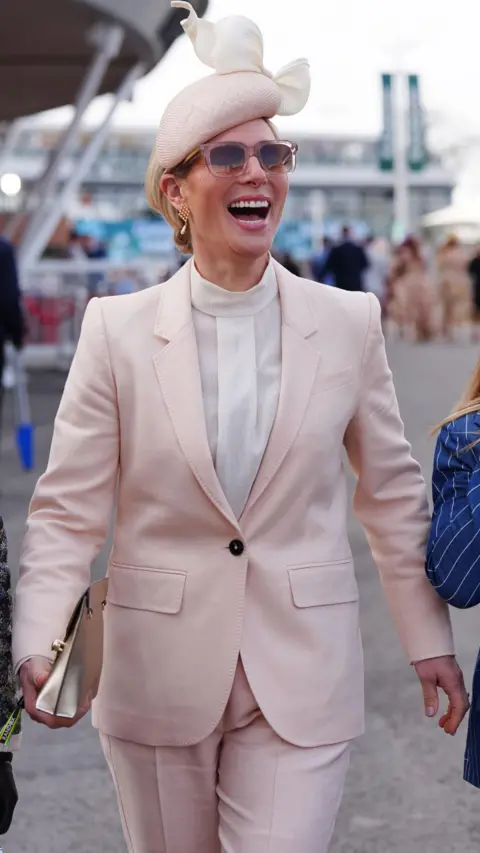 PA Media Zara Tindall wears a peach trouser suit and fascinator and sunglasses on Ladies Day of the Randox Grand National Festival 2026 at Aintree Racecourse
