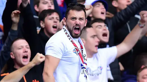 Getty Images A man in a white t-shirt shouting at a Rangers football match