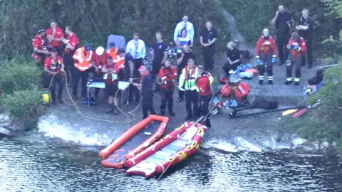 Search and rescue teams at the side of a pond