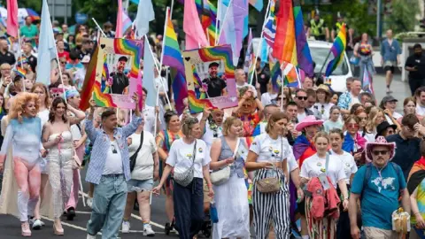Matthew Horwood/Pride Cymru A large crowd of people walking along the street, many of them holding up rainbow flags