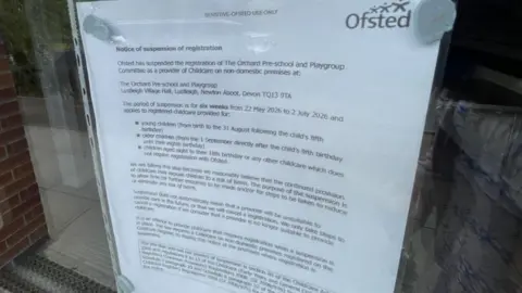 Emma Ruminski/BBC A letter from Ofsted attached to a pane of glass in the building's front door. 