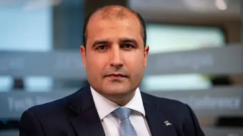 Bloomberg via Getty Images Vishal Marria, Quantexa's chief executive, looks at the camera, wearing a dark suit, white shirt and light blue tie.
