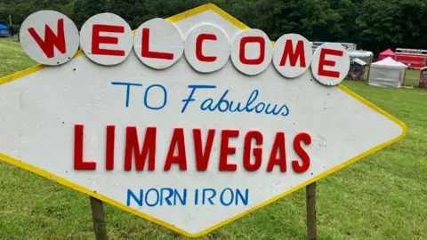 a sign at a festival site, reading "Welcome to fabulous Limavegas Norn Iron"