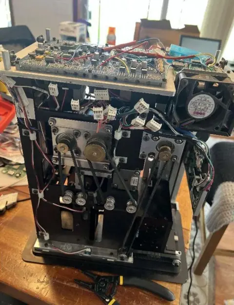 US Department of Justice The inside of a rigged card-shuffling machine shows wires and mechanisms. It is sitting on a desk 