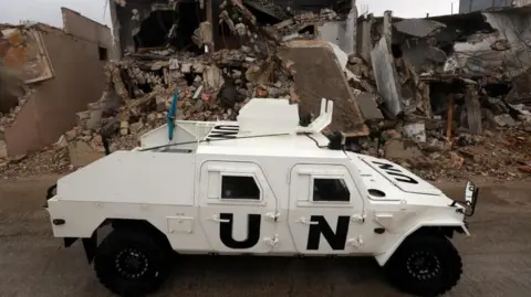 An armoured vehicle of the United Nations Interim Force in Lebanon (UNIFIL) drives next to destroyed buildings in Meiss al-Jabal, Marjayoun district, southern Lebanon, 08 December 2025.