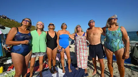 Members of the Gylly Girls sea water swimming society. They are stood on a beach in swimwear.