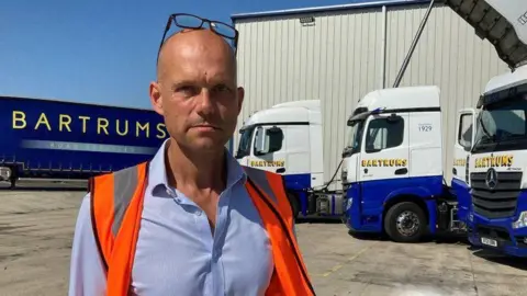 Joe Darlow/BBC Tremanye Johnson standing outside in a shirt and high-visibility jacket