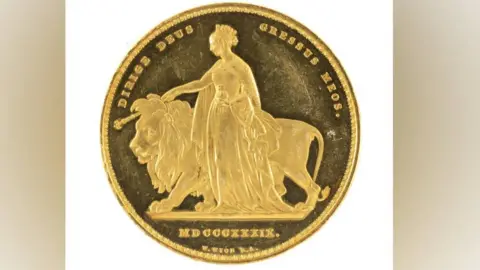 The coin face one showing the queen and the lion side. You can see her cape and the globe she is holding to her hip and the crown on her head. 
