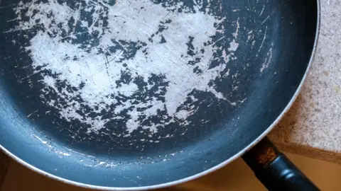 Getty Images Old frying pan with damaged non-stick coating and scratched surface placed on kitchen countertop