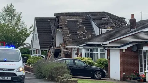 tiles falling down the collapsing roof with emergency services van outside