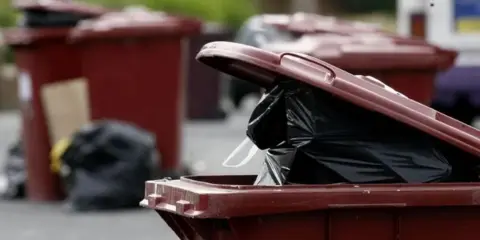 PA Media Black bins poking out of red bin, with more red bins in the background.