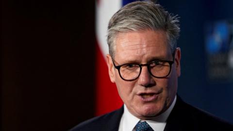 Sir Keir Starmer speaking in front of a Union Jack
