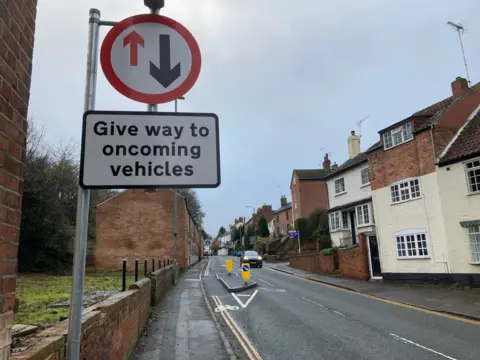 A sign saying Give way near a section of residential road turned into a chicane