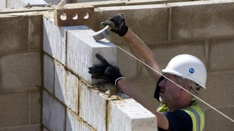 File photo of bricklayer cementing breeze blocks on a wall.