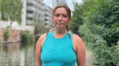 Woman with brown hair with a plait in a turquoise running top 