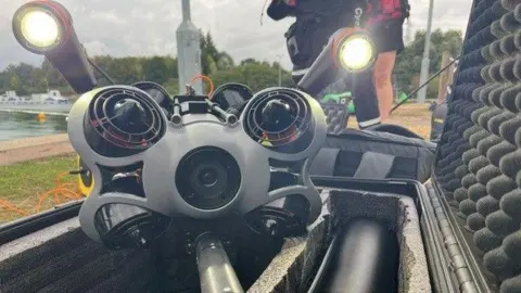 The drone with its lights on, is on display on the shore.