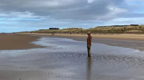 A view of Crosby beach showing an iron man and promenade