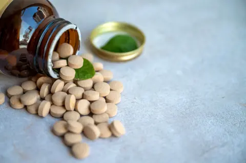 Getty Images Herbal Supplements and green leaves - Ashwagandha capsules