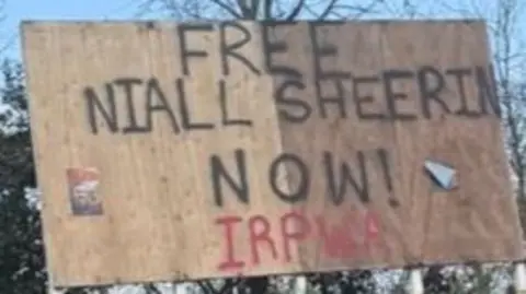 A billboard that says FREE NIALL SHEERIN NOW! IRPWA