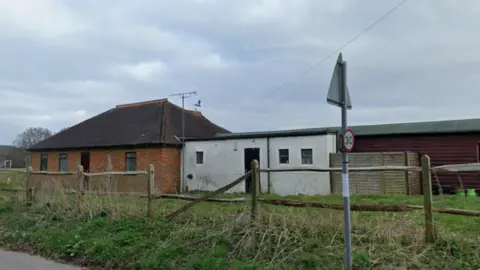 Derelict building in a field with a street sign in the foreground