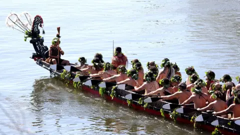 Getty Images Maori warriors wearing wraeths on their heads wait in a boat on a river to carry the remains of Māori King Tuheitia Pōtatau Te Wherowhero VII to Mount Taupiri during his burial ceremony in New Zealand on 5 September