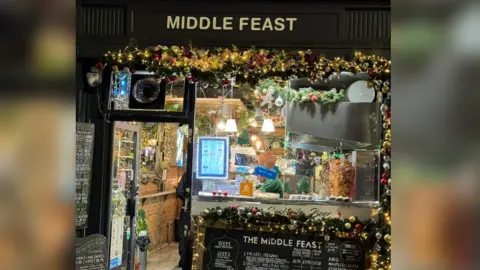 Middle Feast The front window of the Middle Feast restaurant with christmas lights and garlands with baubles. 