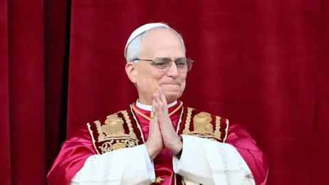 Pope Leo with his hands together in prayer/thanks on the balcony