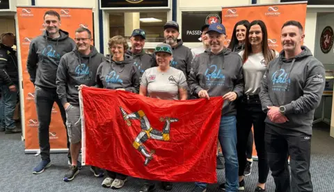 BBC The team of fundraisers gathered holding a Manx flag