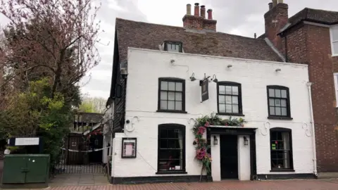 Andrew Marshall/BBC The front view of a restaurant. There are creeping plants on the side of the front door. 
