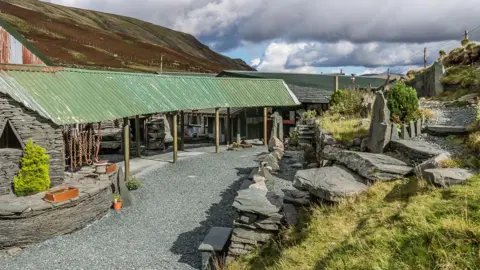 GEOGRAPH / IAN CAPPER The visitor centre at the slate mine at Honister Pass. It's a small building made of slate, with a sloping corrugated iron roof propped up by some posts. Chains are hanging from the roof.