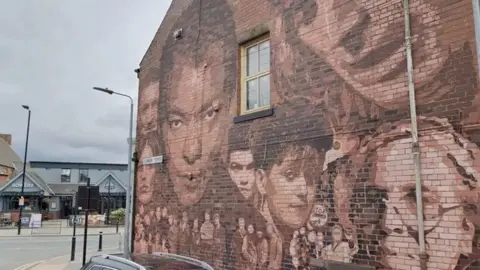 The side of a brick building in Hull, which has been painted with musical figures from Hull, including Roland Gift and Mick Ronson. 