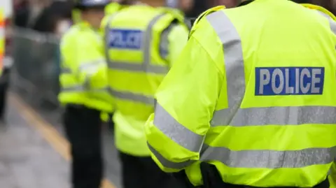 A police officer wearing a high-vis jacket with the word POLICE written on the back