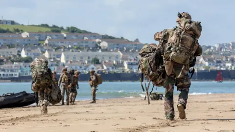Troops walking along the Devon beach towards the sea. 