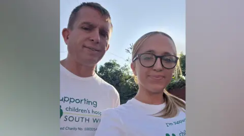 Freya Bird is pictured with her dad. Both are looking directly at the camera and they are wearing white charity T-shirts. The logo on their T-shirts says 'I'm supporting Children's Hospice South West'.