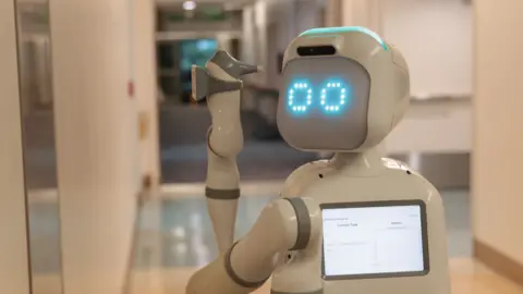 Diligent Robotics The robot Moxi turns its head while travelling in a hospital corridor.