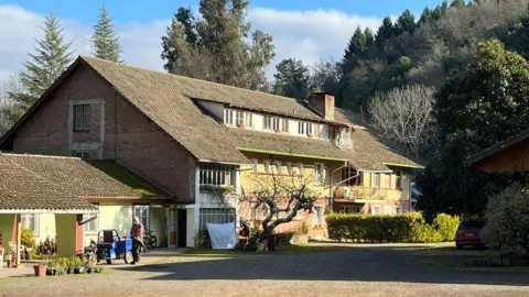 Grace Livingston. A large building can be seen in the surrounding trees. Wash hangs to dry in front of the building. 