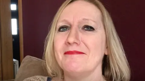 A close up of Jayne looking into the camera.She has short blonde hair and is wearing red lipstick